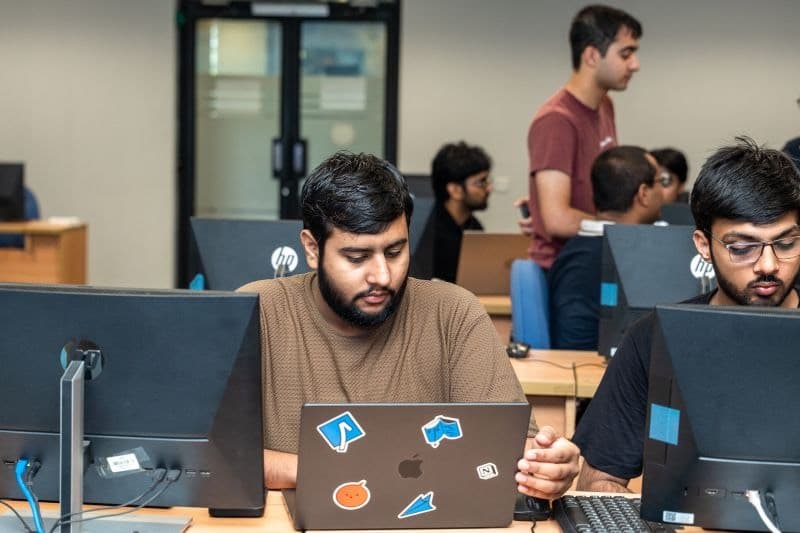 Junaid working at a laptop in a computer lab during a hackathon